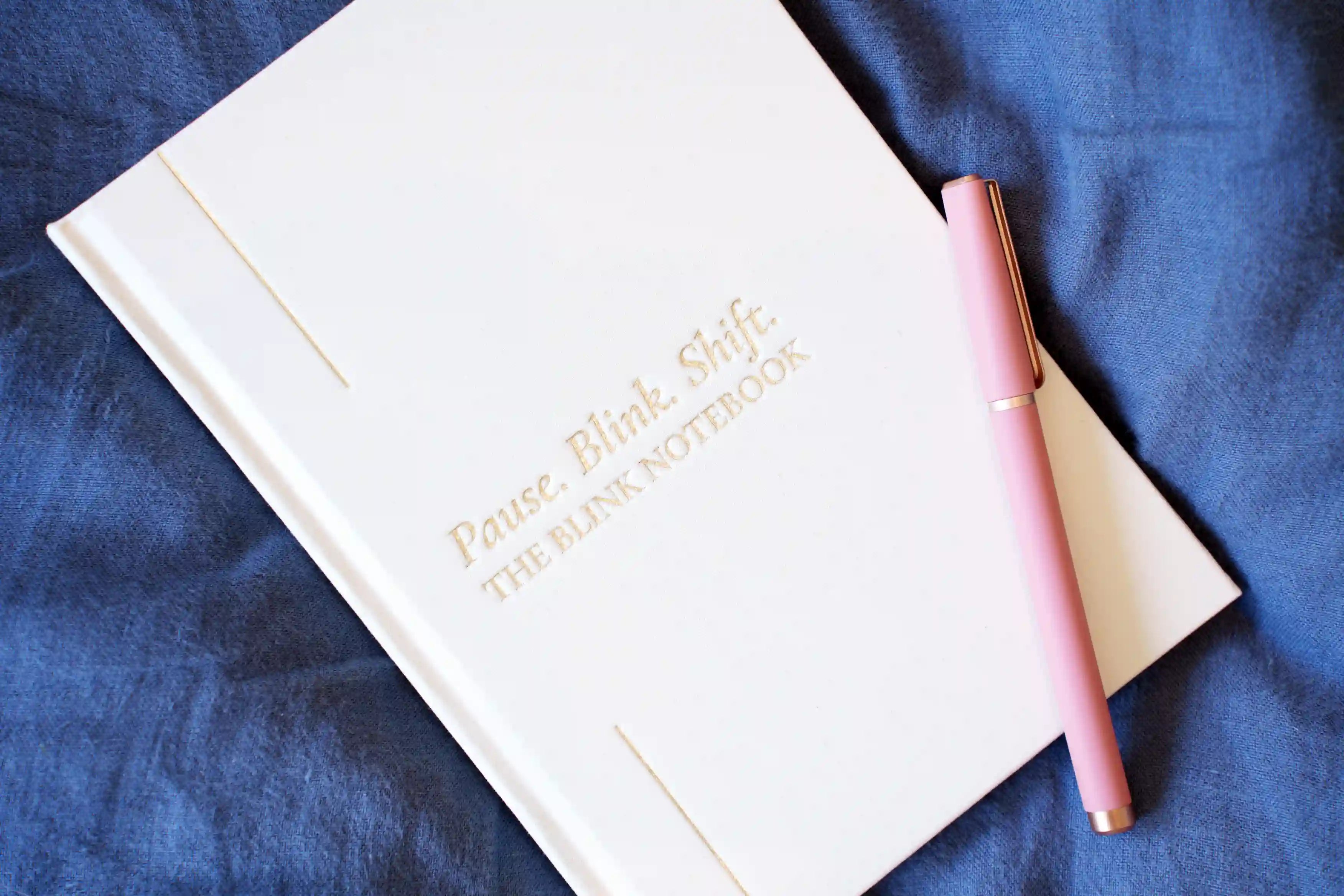blink Notebook with a pen on a blue fabric background
