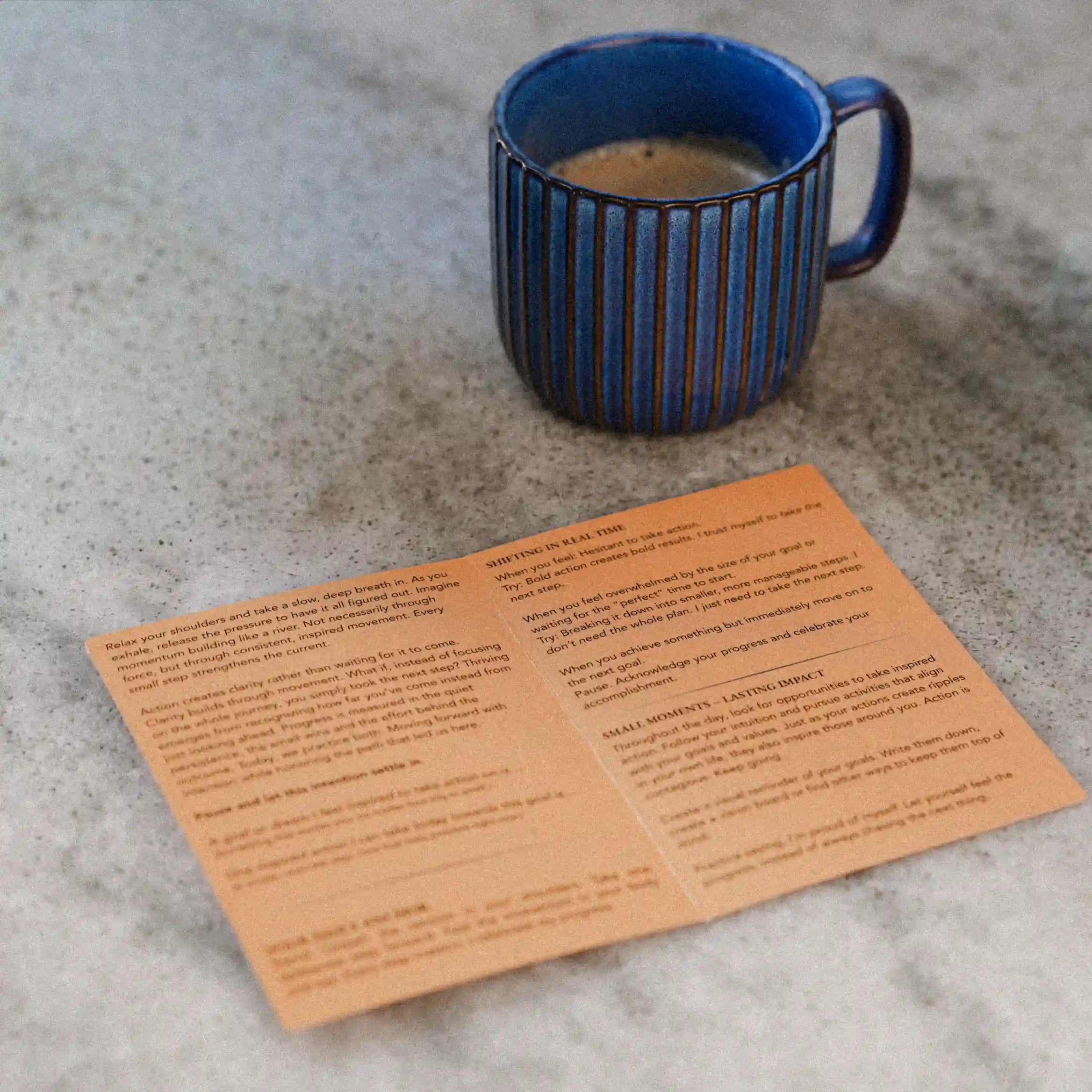 Blue mug with coffee on a textured surface next to a printed blink card.