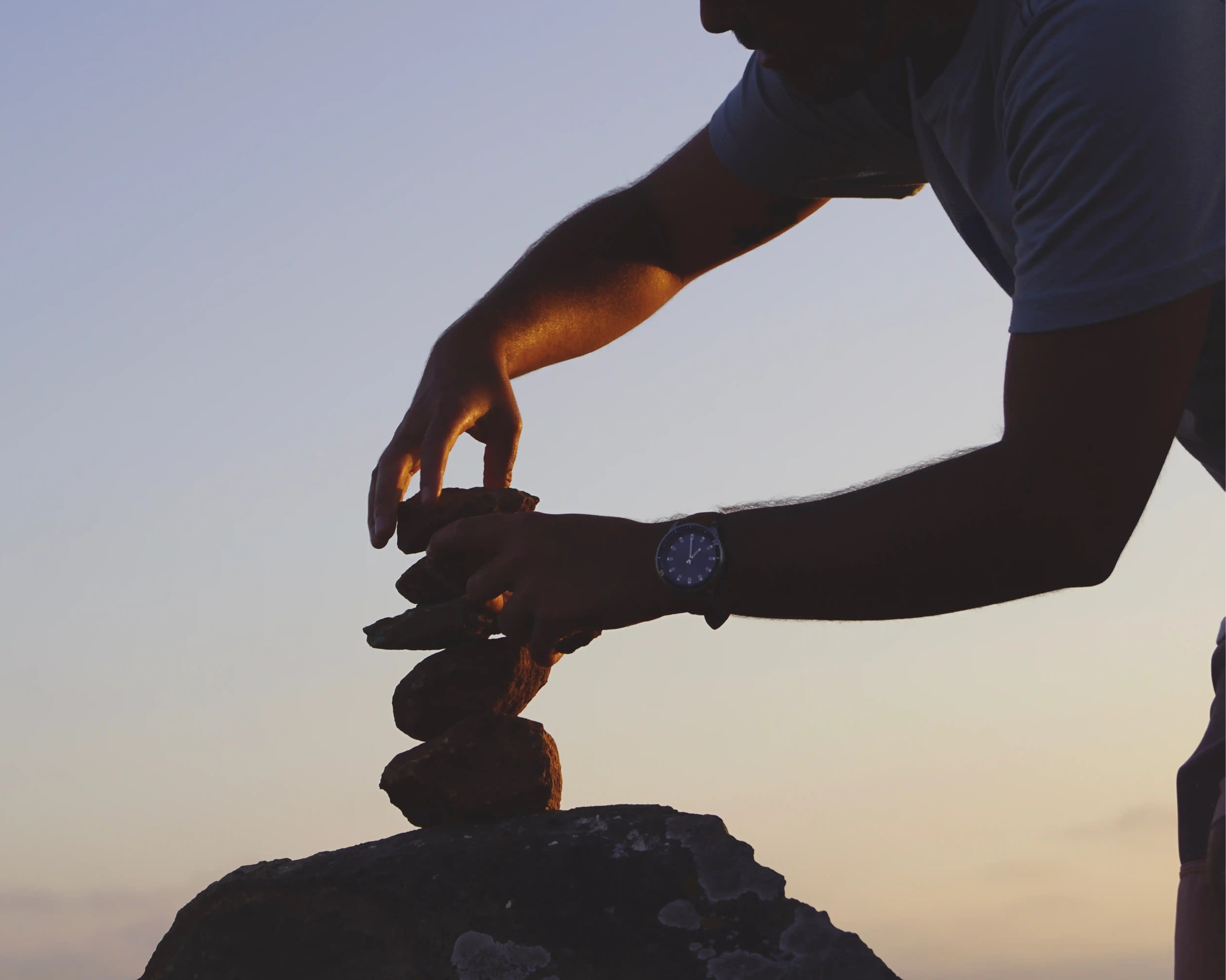 man stacking little rocks to signify growth