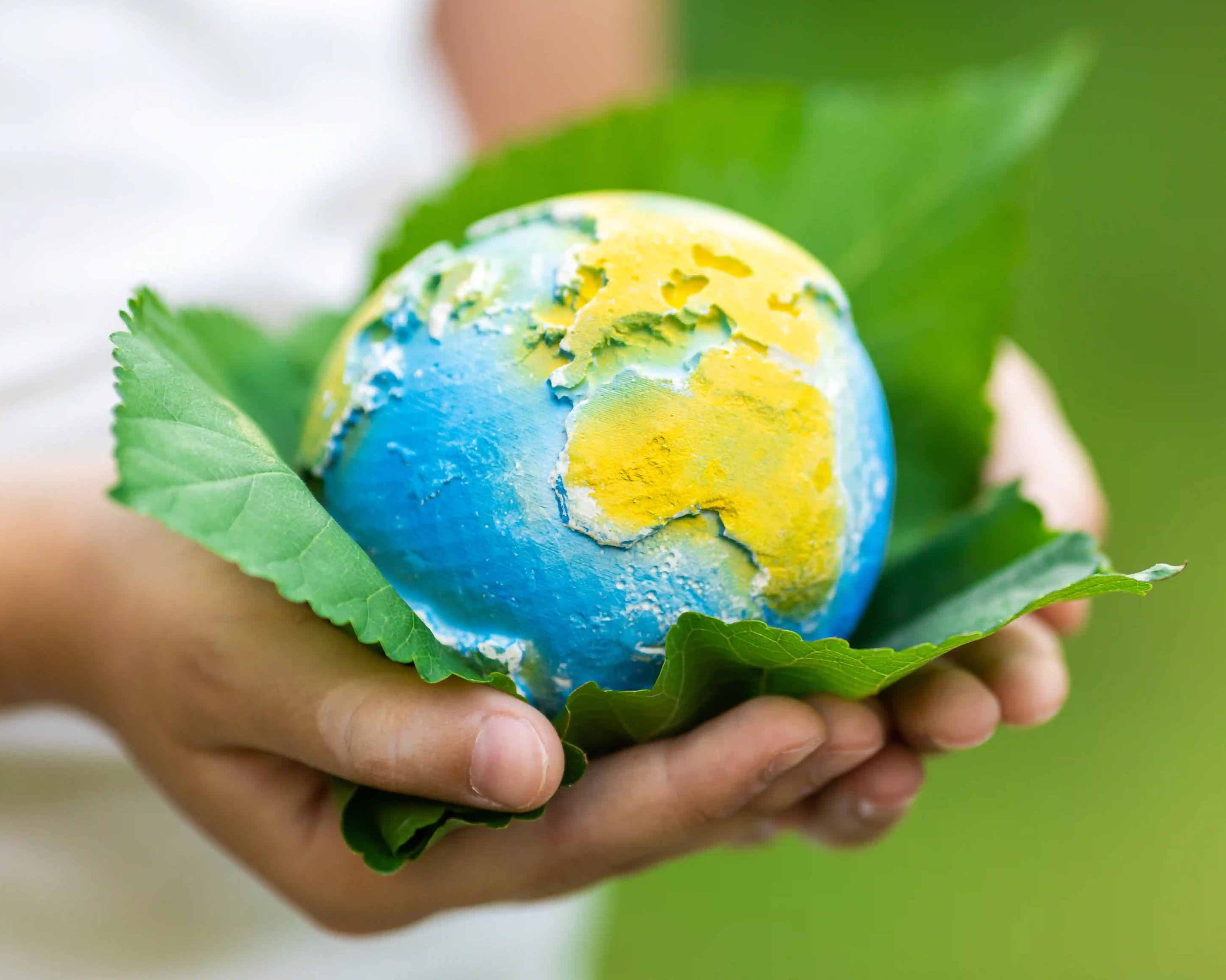 child holding a clay model of planet earth on a green leaf