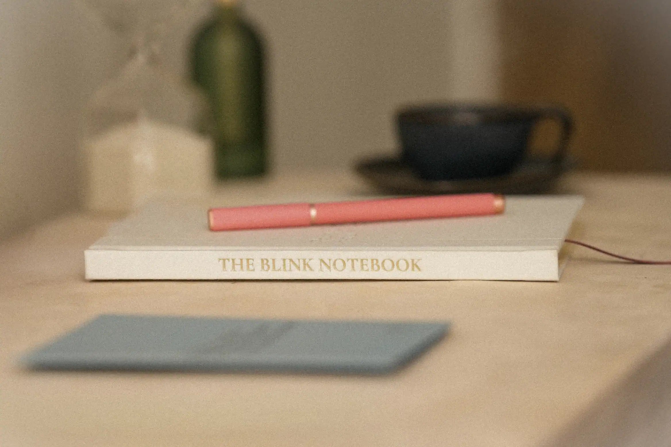 Notebook titled 'The Blink Notebook' with a pen on a surface, blurred background