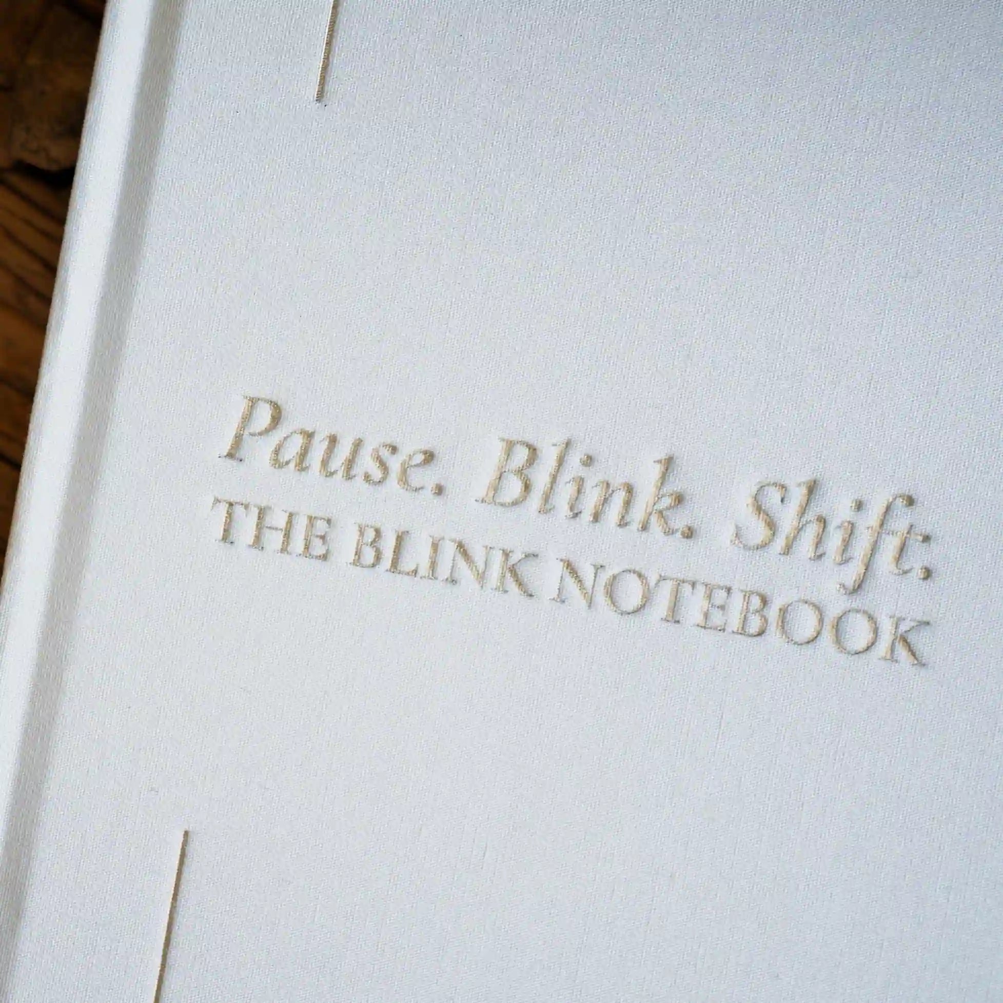 Close-up of a notebook with 'Pause. Blink. Shift.' text on a light background