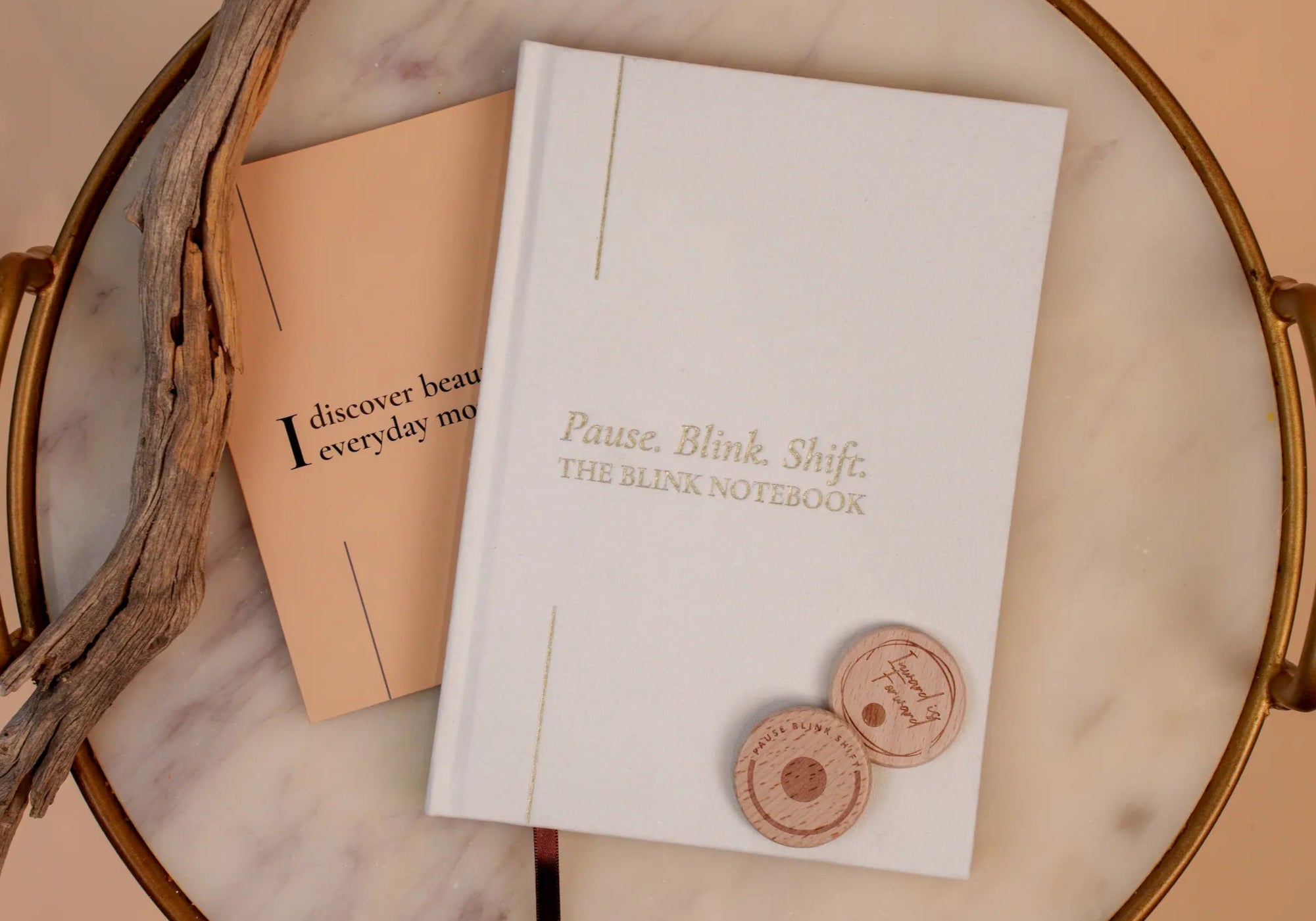 Notebook with 'Pause, Blink, Shift' text on a marble surface with decorative elements.