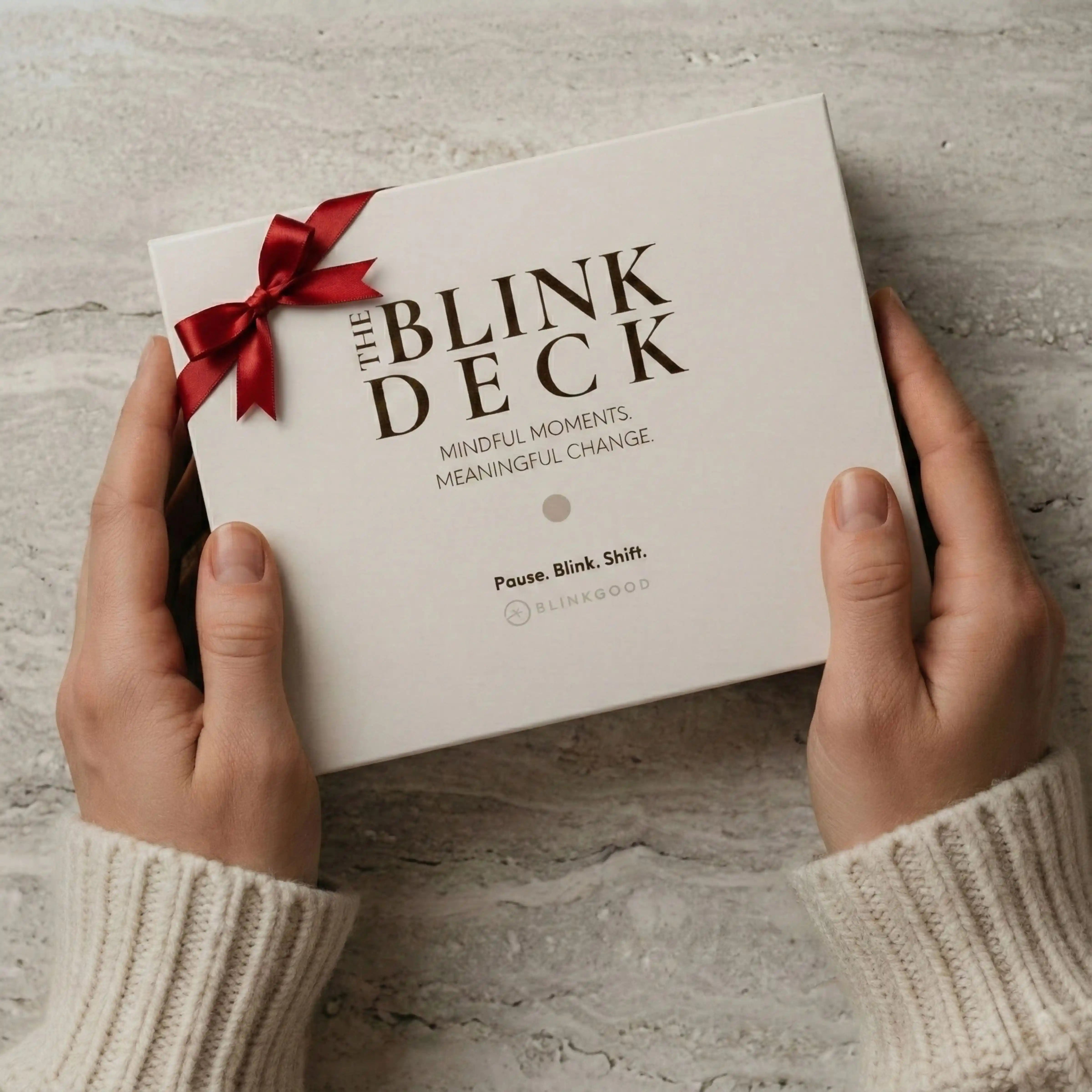 Person holding 'The Blink Deck' against a textured beige background