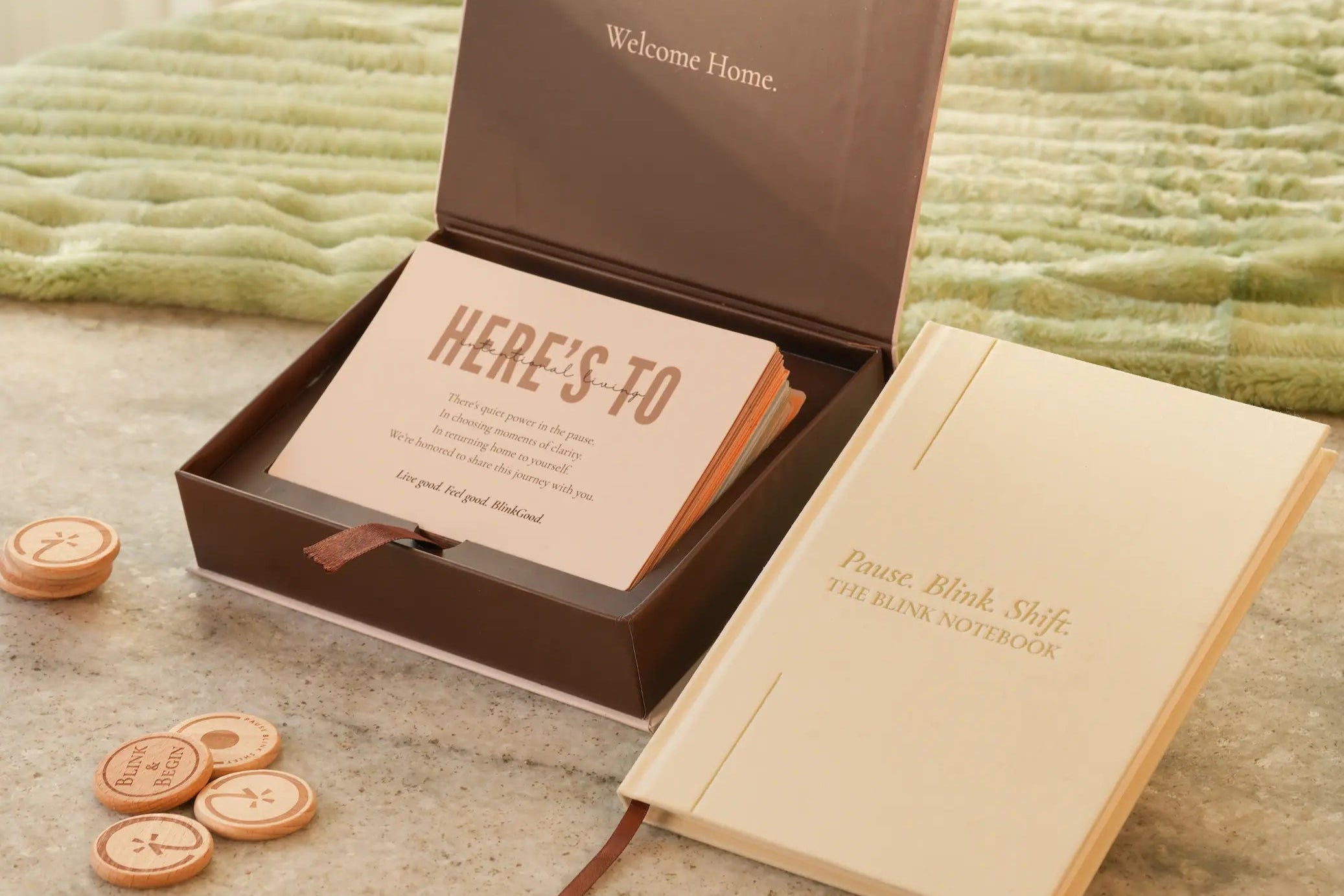 Notebook with 'Here's To' card and 'Welcome Home' message on a textured surface.